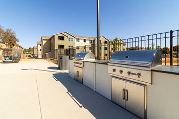 two stainless steel barbecue grills on a patio with apartments in the background